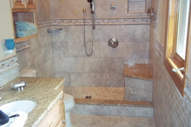Doorless shower - large traditional master porcelain tile and beige tile porcelain tile doorless shower idea in Milwaukee with beige walls, raised-panel cabinets, light wood cabinets, a two-piece toilet, an undermount sink and granite countertops