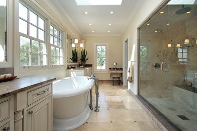 Cette photo montre une grande salle de bain chic avec des portes de placard beiges, un plan de toilette en granite, une baignoire indépendante, un placard avec porte à panneau surélevé, un mur jaune, un sol en carrelage de céramique, un lavabo encastré, un sol beige et une cabine de douche à porte battante.