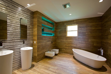 他の地域にある広いモダンスタイルのおしゃれなマスターバスルーム (ペデスタルシンク、置き型浴槽、壁掛け式トイレ、茶色いタイル) の写真