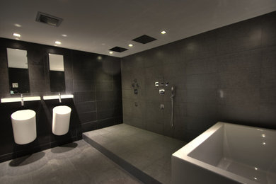 Ejemplo de cuarto de baño principal minimalista con bañera exenta, ducha abierta, sanitario de pared, baldosas y/o azulejos grises, baldosas y/o azulejos de cerámica y paredes grises