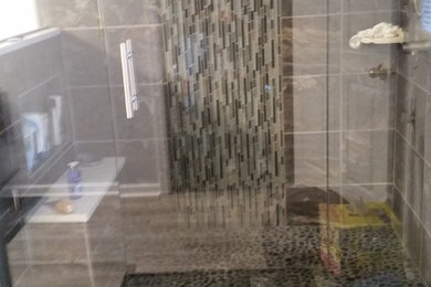 Example of a mid-sized minimalist master gray tile and ceramic tile ceramic tile doorless shower design in Other with a vessel sink, glass-front cabinets, black cabinets, marble countertops, a two-piece toilet and blue walls