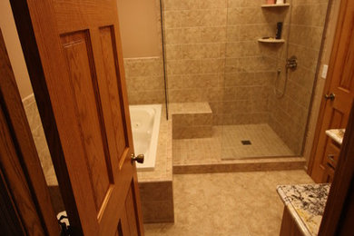 ミネアポリスにある中くらいなトランジショナルスタイルのおしゃれなマスターバスルーム (アンダーカウンター洗面器、レイズドパネル扉のキャビネット、中間色木目調キャビネット、御影石の洗面台、ドロップイン型浴槽、オープン型シャワー、分離型トイレ、ベージュのタイル、セラミックタイル、ベージュの壁、セラミックタイルの床) の写真