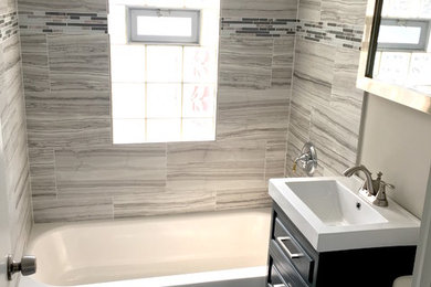 Diseño de cuarto de baño actual con combinación de ducha y bañera, baldosas y/o azulejos grises, baldosas y/o azulejos de cerámica, paredes grises, suelo de baldosas de cerámica y lavabo integrado