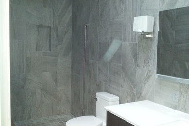 Mid-sized transitional 3/4 gray tile and porcelain tile porcelain tile and gray floor alcove shower photo in Oklahoma City with flat-panel cabinets, dark wood cabinets, a one-piece toilet, gray walls, an integrated sink, quartz countertops, a hinged shower door and white countertops