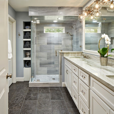 Elegant master gray tile corner shower photo in Dallas with white cabinets, an undermount sink, recessed-panel cabinets and gray walls