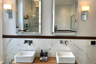 Design ideas for a large contemporary ensuite bathroom in London with freestanding cabinets, medium wood cabinets, a freestanding bath, a double shower, a one-piece toilet, marble flooring, a wall-mounted sink, wooden worktops, grey floors and a sliding door.