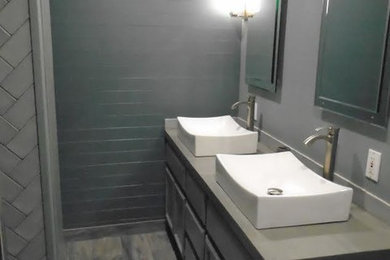 Bathroom - mid-sized contemporary 3/4 gray tile and subway tile vinyl floor and gray floor bathroom idea in Austin with recessed-panel cabinets, gray cabinets, solid surface countertops, gray countertops, a two-piece toilet, gray walls and a vessel sink