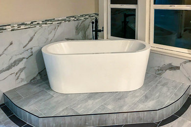 Mid-sized minimalist master gray floor freestanding bathtub photo in Orange County with beige walls and an undermount sink