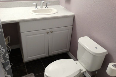 Cette photo montre une salle de bain principale tendance de taille moyenne avec un lavabo posé, un placard à porte plane, des portes de placard blanches, un plan de toilette en surface solide, une baignoire posée, un combiné douche/baignoire, WC séparés, un carrelage gris, des carreaux de céramique et un mur violet.