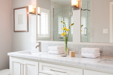 Cette photo montre une douche en alcôve principale tendance de taille moyenne avec un placard à porte shaker, des portes de placard blanches, WC séparés, un mur gris, un lavabo encastré et un plan de toilette en marbre.