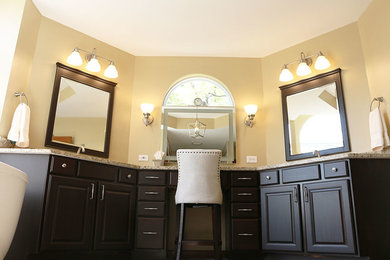 Bild på ett stort beige beige en-suite badrum, med luckor med upphöjd panel, bruna skåp, ett fristående badkar, en dusch i en alkov, en toalettstol med separat cisternkåpa, beige kakel, keramikplattor, beige väggar, klinkergolv i keramik, ett undermonterad handfat, granitbänkskiva, flerfärgat golv och dusch med gångjärnsdörr