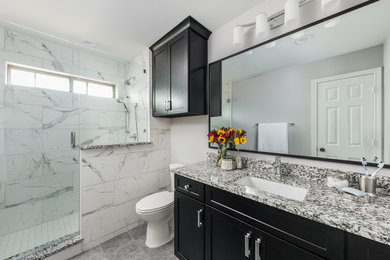 Inspiration for a medium sized modern bathroom in Dallas with shaker cabinets, black cabinets, an alcove shower, a two-piece toilet, white tiles, marble tiles, grey walls, ceramic flooring, a submerged sink, quartz worktops, grey floors, a hinged door and multi-coloured worktops.