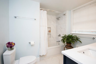 This is an example of a medium sized modern ensuite bathroom in Providence with beaded cabinets, blue cabinets, a built-in bath, a walk-in shower, a one-piece toilet, white tiles, ceramic tiles, blue walls, ceramic flooring, a submerged sink, tiled worktops, white floors and a shower curtain.