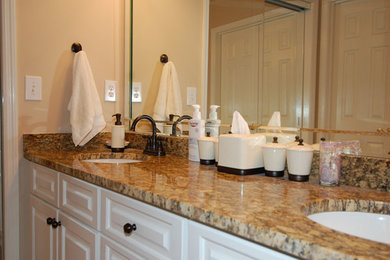 Foto de cuarto de baño principal tradicional de tamaño medio con armarios con paneles con relieve, puertas de armario blancas, paredes beige, lavabo bajoencimera y encimera de granito