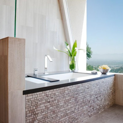 Example of a large trendy master gray tile and porcelain tile porcelain tile and gray floor freestanding bathtub design in Los Angeles with an undermount sink, flat-panel cabinets, dark wood cabinets, white walls, a one-piece toilet and solid surface countertops