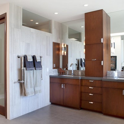 Inspiration for a large contemporary master gray tile and porcelain tile porcelain tile and gray floor freestanding bathtub remodel in Los Angeles with an undermount sink, flat-panel cabinets, dark wood cabinets, solid surface countertops, white walls, a one-piece toilet and gray countertops