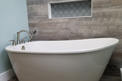 Example of a mid-sized transitional brown tile and porcelain tile medium tone wood floor and brown floor freestanding bathtub design in Other with gray walls