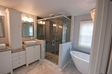 Réalisation d'une grande salle de bain principale minimaliste avec une vasque, un placard avec porte à panneau surélevé, des portes de placard blanches, une baignoire indépendante, une douche d'angle, un mur gris et un sol en marbre.