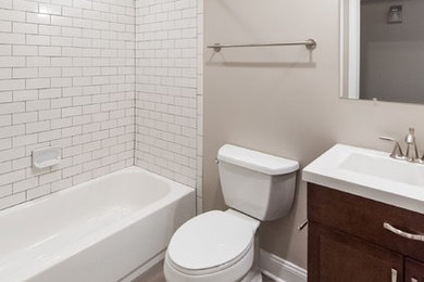 Bathroom - mid-sized traditional master porcelain tile and beige floor bathroom idea in DC Metro with shaker cabinets, dark wood cabinets, a two-piece toilet, beige walls, an integrated sink and solid surface countertops