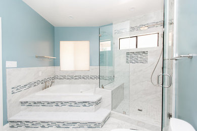 Photo of a medium sized modern ensuite bathroom in Los Angeles with shaker cabinets, blue cabinets, a built-in bath, a corner shower, a one-piece toilet, white tiles, marble tiles, blue walls, marble flooring, a submerged sink, quartz worktops, white floors, a hinged door and white worktops.