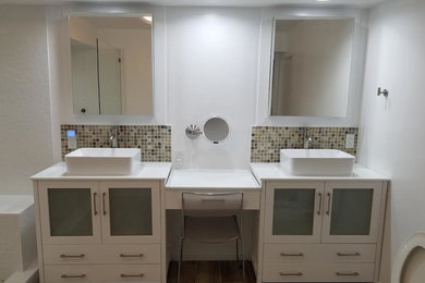 Large trendy master beige tile, brown tile, gray tile, multicolored tile and mosaic tile brown floor and porcelain tile bathroom photo in Los Angeles with furniture-like cabinets, white cabinets, a two-piece toilet, white walls, a vessel sink and quartz countertops