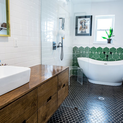Bathroom - eclectic master green tile black floor bathroom idea in Houston with flat-panel cabinets, medium tone wood cabinets, white walls, a vessel sink, wood countertops and brown countertops