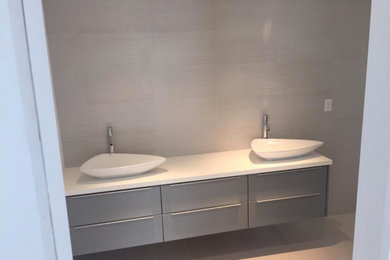 Diseño de cuarto de baño clásico renovado de tamaño medio con armarios con paneles lisos, puertas de armario grises, paredes blancas, suelo de baldosas de porcelana y lavabo sobreencimera