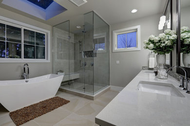 Design ideas for a medium sized modern ensuite bathroom in Tampa with shaker cabinets, a two-piece toilet, beige tiles, engineered stone worktops, beige floors, grey worktops, a freestanding bath, a corner shower, grey walls, a submerged sink, a hinged door and dark wood cabinets.