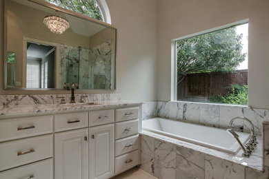 Exemple d'une salle d'eau chic de taille moyenne avec un placard avec porte à panneau surélevé, des portes de placard blanches, une baignoire posée, un carrelage gris, un carrelage blanc, du carrelage en marbre, un mur beige, un lavabo encastré et un plan de toilette en marbre.