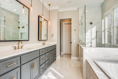Example of a large transitional master gray tile and marble tile marble floor and beige floor bathroom design in Other with recessed-panel cabinets, gray cabinets, beige walls, an undermount sink, solid surface countertops, a hinged shower door and white countertops