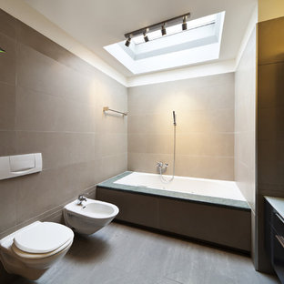 Ispirazione per una stanza da bagno padronale minimal di medie dimensioni con ante lisce, ante nere, vasca da incasso, bidè, piastrelle grigie, pareti beige, pavimento in legno verniciato, lavabo a bacinella, top in vetro e doccia aperta
