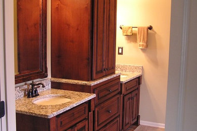 Example of a mid-sized classic master porcelain tile and beige floor bathroom design in Kansas City with raised-panel cabinets, dark wood cabinets, beige walls, an undermount sink and granite countertops