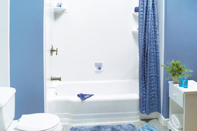 Modelo de cuarto de baño clásico de tamaño medio con armarios con paneles lisos, puertas de armario blancas, bañera empotrada, combinación de ducha y bañera, sanitario de dos piezas, paredes azules, suelo de baldosas de cerámica, aseo y ducha, suelo gris y ducha con cortina