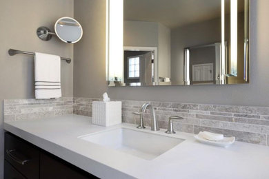 Exemple d'une petite salle d'eau chic en bois foncé avec un carrelage gris, des carreaux en allumettes, un mur gris, un lavabo encastré, un plan de toilette en quartz modifié et un plan de toilette blanc.
