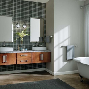 Foto på ett stort funkis en-suite badrum, med släta luckor, skåp i mellenmörkt trä, ett badkar med tassar, blå kakel, keramikplattor, grå väggar, klinkergolv i porslin, ett fristående handfat, bänkskiva i återvunnet glas och brunt golv