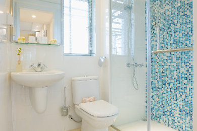ロサンゼルスにある中くらいなトランジショナルスタイルのおしゃれなバスルーム (浴槽なし) (オープンシェルフ、白いキャビネット、コーナー設置型シャワー、分離型トイレ、青いタイル、モザイクタイル、白い壁、セラミックタイルの床、壁付け型シンク、ベージュの床、開き戸のシャワー) の写真