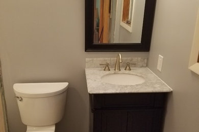 Inspiration for a small timeless 3/4 ceramic tile and beige floor bathroom remodel in Cleveland with flat-panel cabinets, dark wood cabinets, a two-piece toilet, gray walls, an undermount sink and quartzite countertops