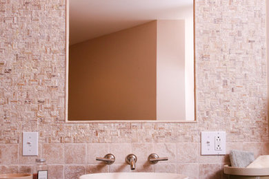 Imagen de cuarto de baño contemporáneo con armarios con paneles lisos, puertas de armario de madera clara, baldosas y/o azulejos beige, baldosas y/o azulejos de piedra, paredes beige, lavabo sobreencimera y encimera de granito