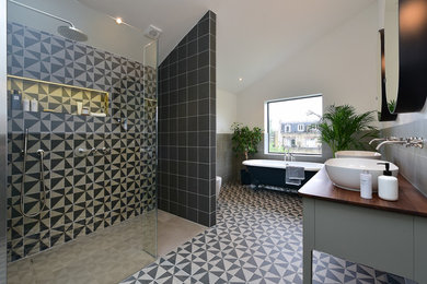 ロンドンにある広いモダンスタイルのおしゃれな浴室 (グレーのキャビネット、猫足バスタブ、ベージュのタイル、黒いタイル、セメントタイル、白い壁、セメントタイルの床、ベッセル式洗面器、木製洗面台、マルチカラーの床、ブラウンの洗面カウンター) の写真