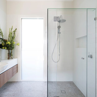 This is an example of a mid-sized contemporary 3/4 bathroom in Melbourne with medium wood cabinets, white tile, porcelain tile, white walls, porcelain floors, engineered quartz benchtops, beige floor, a hinged shower door, white benchtops, flat-panel cabinets, a corner shower and a drop-in sink.