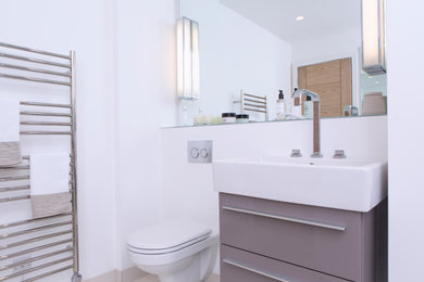 Photo of a medium sized modern ensuite bathroom in Gloucestershire with a wall mounted toilet, white walls, ceramic flooring and a freestanding vanity unit.