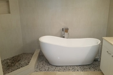 Inspiration for a contemporary beige tile and porcelain tile pebble tile floor freestanding bathtub remodel in Miami with flat-panel cabinets, white cabinets, beige walls and a drop-in sink