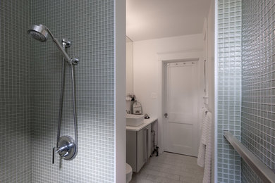 Inspiration for a small modern master glass tile alcove shower remodel in Baltimore with a vessel sink, flat-panel cabinets, solid surface countertops, a one-piece toilet and white walls