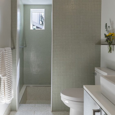 Bathroom - small modern master glass tile and green tile gray floor and terrazzo floor bathroom idea in Baltimore with a vessel sink, flat-panel cabinets, solid surface countertops, a one-piece toilet, white walls and gray cabinets