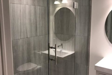 Inspiration for a mid-sized modern 3/4 porcelain tile and gray floor alcove shower remodel in Toronto with flat-panel cabinets, white cabinets, gray walls, an integrated sink, a hinged shower door and white countertops