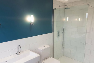 Идея дизайна: детская ванная комната среднего размера в стиле модернизм с душем без бортиков, белой плиткой, керамической плиткой, синими стенами, подвесной раковиной и душем с распашными дверями