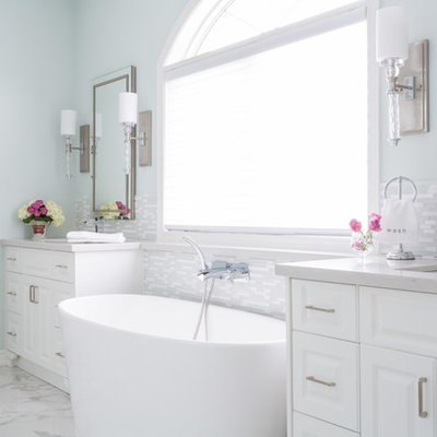 Inspiration for a large timeless master white tile and matchstick tile marble floor freestanding bathtub remodel in Toronto with raised-panel cabinets, an undermount sink, blue walls, white cabinets, a two-piece toilet and granite countertops