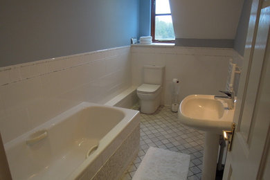 Contemporary bathroom in Cambridgeshire with a built-in bath, a one-piece toilet, grey tiles, mosaic tiles, blue walls, marble flooring and a pedestal sink.