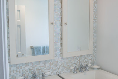 ニューヨークにあるラグジュアリーな小さなトランジショナルスタイルのおしゃれな子供用バスルーム (オーバーカウンターシンク、レイズドパネル扉のキャビネット、白いキャビネット、人工大理石カウンター、ドロップイン型浴槽、シャワー付き浴槽	、分離型トイレ、マルチカラーのタイル、ガラスタイル、白い壁、大理石の床) の写真