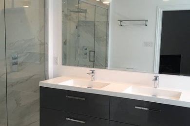 Inspiration for a mid-sized modern master white tile and ceramic tile ceramic tile and white floor bathroom remodel in Ottawa with flat-panel cabinets, gray cabinets, a one-piece toilet, white walls, an integrated sink, solid surface countertops, a hinged shower door and white countertops
